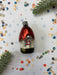 a red ornament with a black base, surrounded by scattered confetti and a green pine branch.