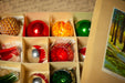 A collection of colorful Christmas ornaments in various shapes and sizes, arranged in a box.
