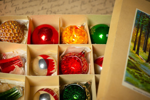A collection of colorful Christmas ornaments in various shapes and sizes, arranged in a box.