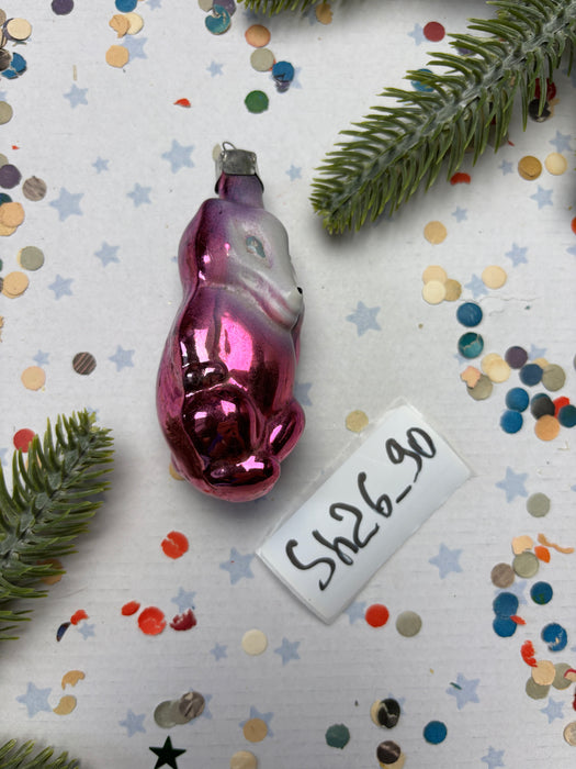 a pink ornament, a piece of paper with the number "069745", and some confetti on a white background.