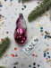 a pink ornament, a piece of paper with the number "069745", and some confetti on a white background.