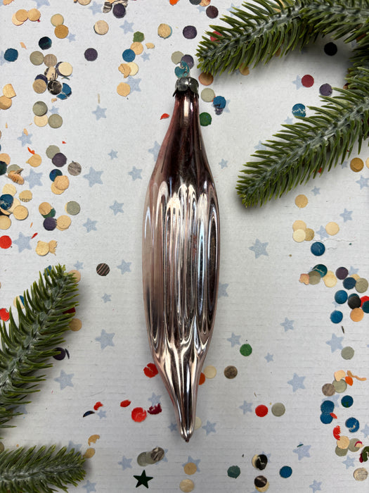 a shiny metallic ornament placed on a white background, surrounded by colorful confetti and pine branches.