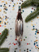 a shiny metallic ornament placed on a white background, surrounded by colorful confetti and pine branches.