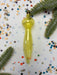 a yellow ornament with a pointed end, surrounded by confetti and green pine branches.