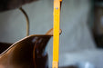 A close-up view of a metal object, possibly a ruler or measuring tool, with a yellow measuring scale on it. The object appears to be made of a shiny, metallic material and is positioned vertically.