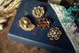 a collection of ornate jewelry, including brooches and buttons, placed on top of a blue book with gold lettering.
