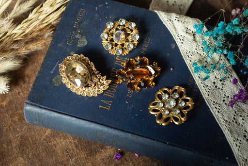 a collection of ornate jewelry, including brooches and buttons, placed on top of a blue book with gold lettering.