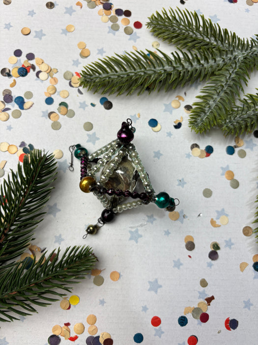 a Christmas ornament with a star-shaped design, surrounded by pine branches, confetti, and other festive decorations.