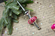 a Christmas ornament with a red and gold design, placed on a surface with handwritten text and small star decorations.