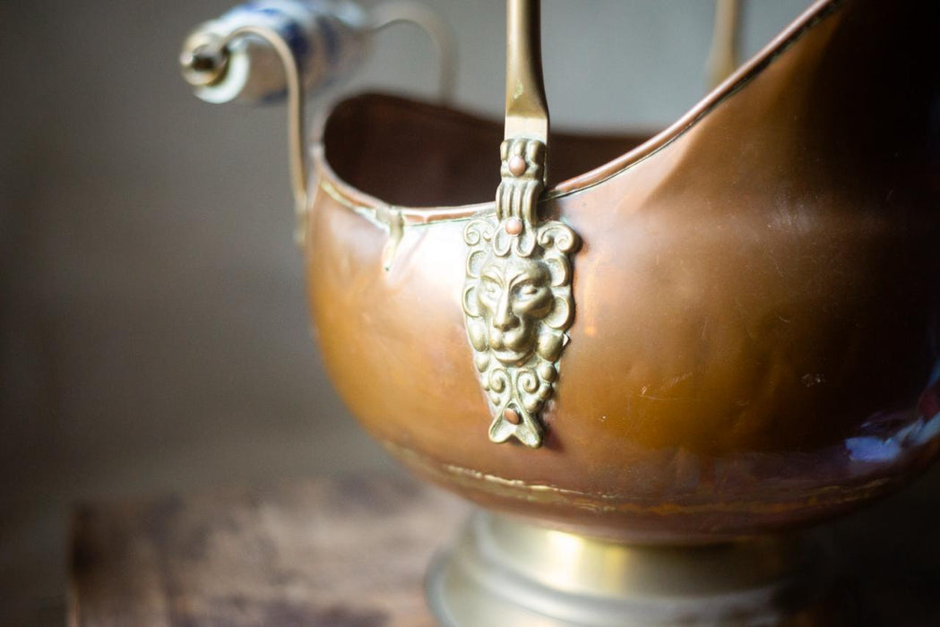 A close-up image of a decorative metal bowl or container with a lion's head or face on it, placed on a wooden surface.