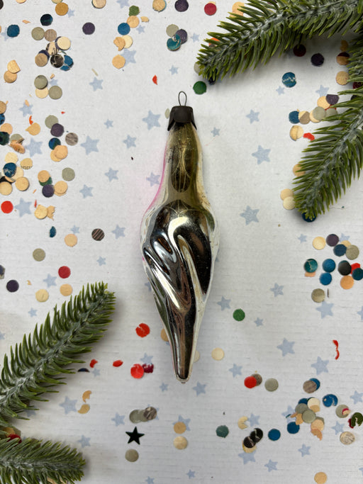 a silver ornament with a pointed end, surrounded by colorful confetti and green pine branches.