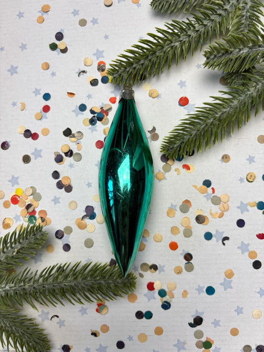 a green ornament, possibly a Christmas ornament, surrounded by colorful confetti and pine branches.