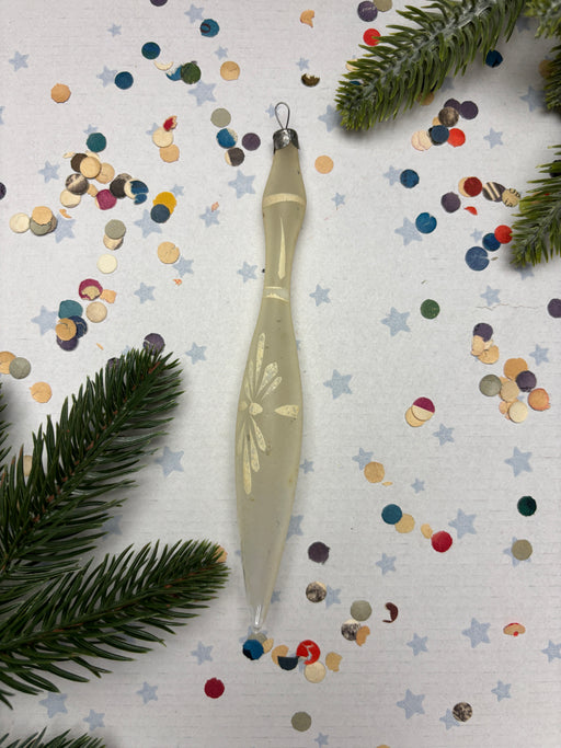 a decorative object, possibly a candle or ornament, surrounded by colorful confetti and pine branches.