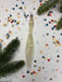 a decorative object, possibly a candle or ornament, surrounded by colorful confetti and pine branches.