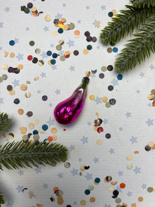 A pink ornament is surrounded by colorful confetti and green pine branches on a white background.